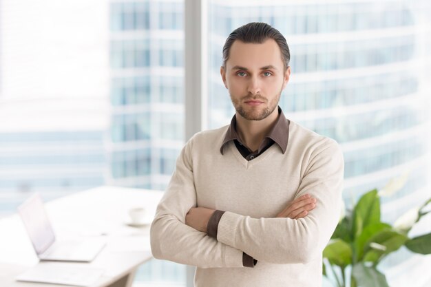 Riuscito giovane uomo d&#39;affari serio che sta nell&#39;ufficio che esamina macchina fotografica