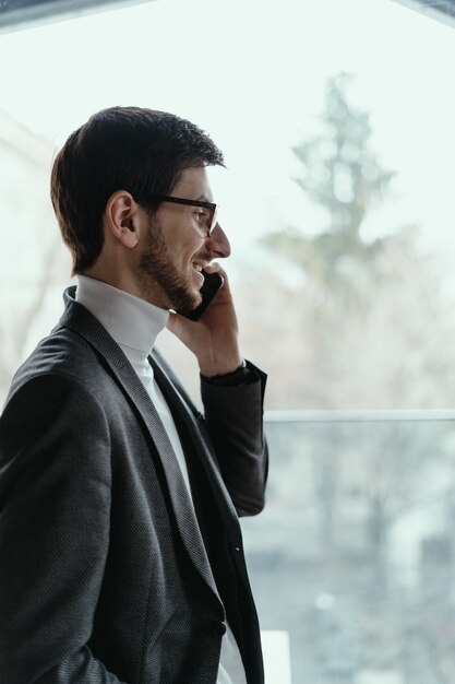 Riuscito uomo di affari del ritratto che parla sullo smartphone