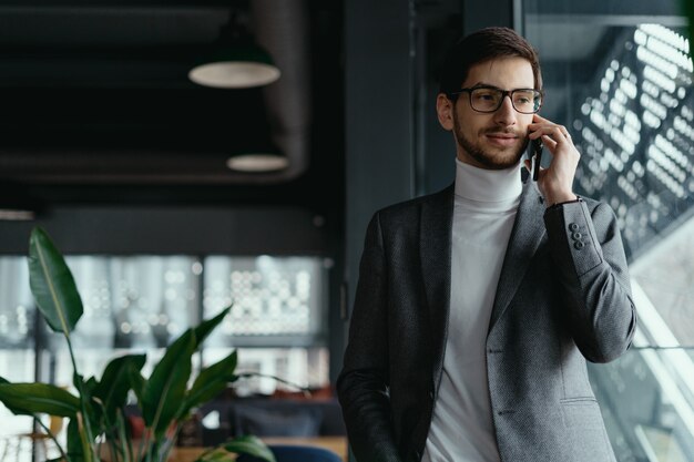 Riuscito uomo di affari del ritratto che parla sullo smartphone