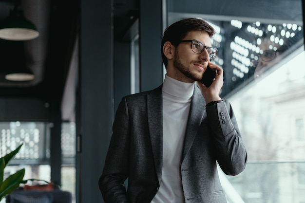 Riuscito uomo di affari del ritratto che parla sullo smartphone