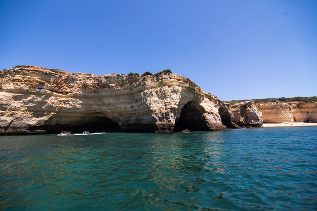 Rocce, scogliere e paesaggio dell'oceano al litorale in Algarve, Portogallo vista dalla barca