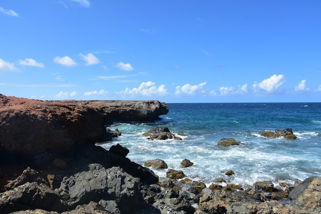 Roccia lavica nera con onde che sbarcano ad Aruba