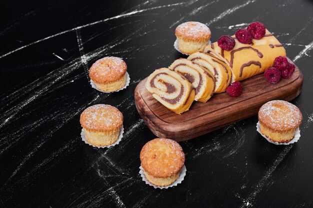 Rollcake con frutti di bosco su un vassoio con muffin.