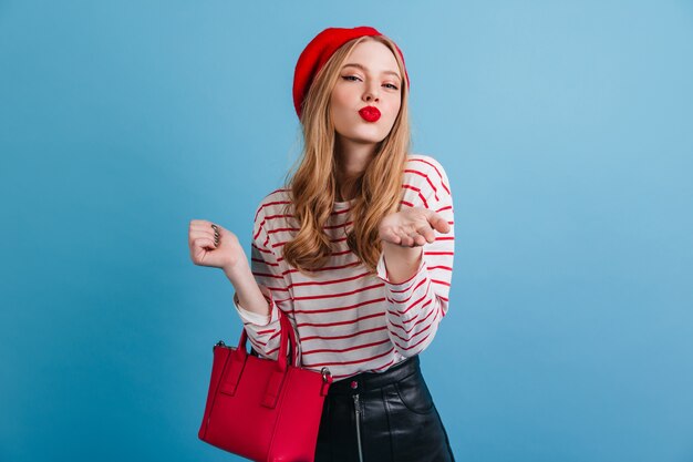 Romantica ragazza francese. Donna alla moda in berretto che tiene borsetta rossa.