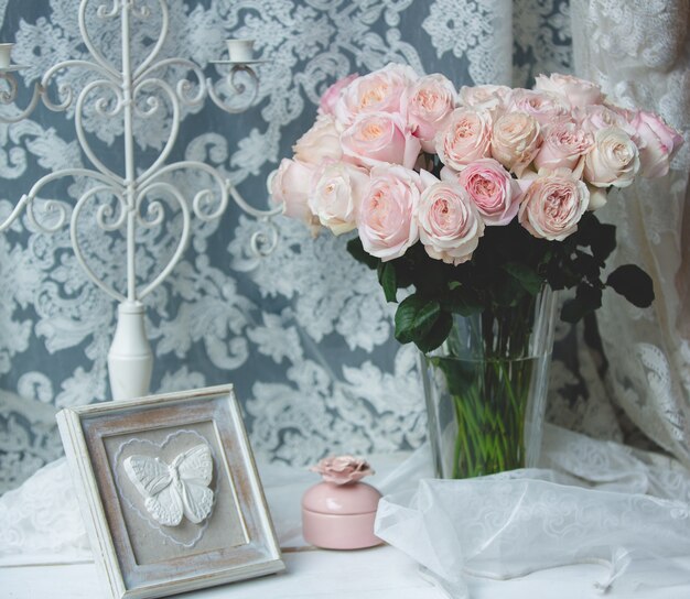 Rose rosa in un vaso di vetro con accessori per il matrimonio