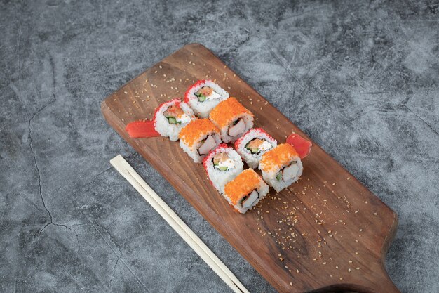 Rotoli di sushi con frutti di mare e caviale rosso isolato su un piatto di legno.