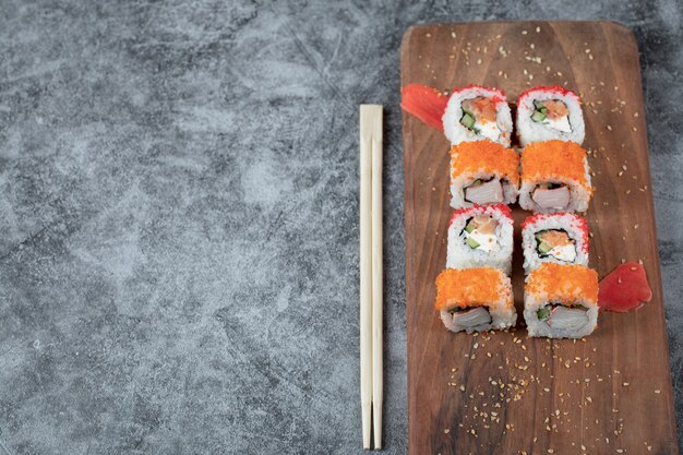 Rotoli di sushi con frutti di mare e caviale rosso isolato su un piatto di legno.