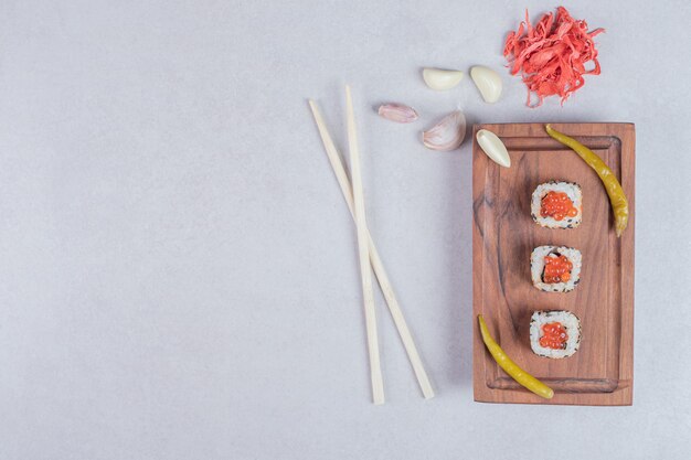 Rotoli di sushi dell'Alaska decorati con caviale rosso su sfondo bianco con bacchette e zenzero sottaceto.
