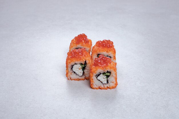 Rotoli di sushi freschi tradizionali sulla superficie bianca.