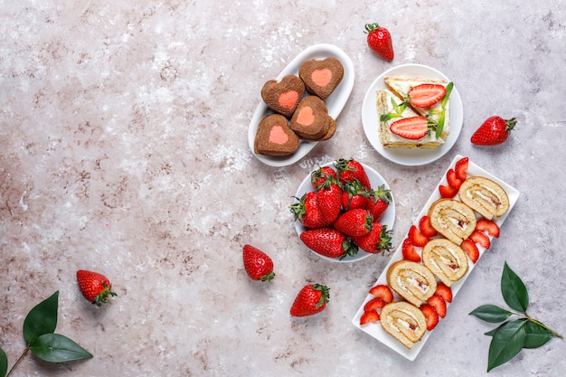 Rotolo delizioso del dolce della fragola, biscotti a forma di cuore, fette del dolce con le fragole fresche, vista superiore