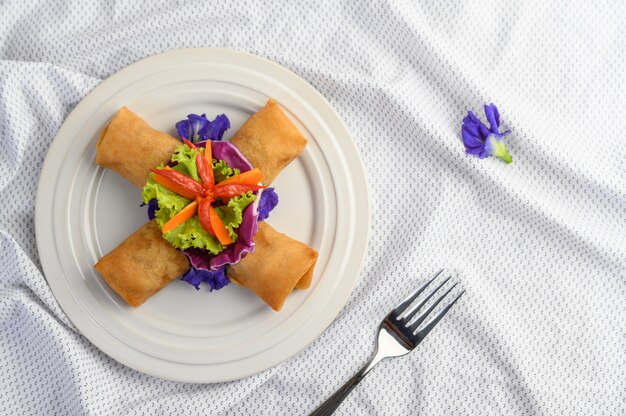 Rotolo dell'uovo o Fried Spring Rolls sull'alimento tailandese del piatto bianco. Vista dall'alto.