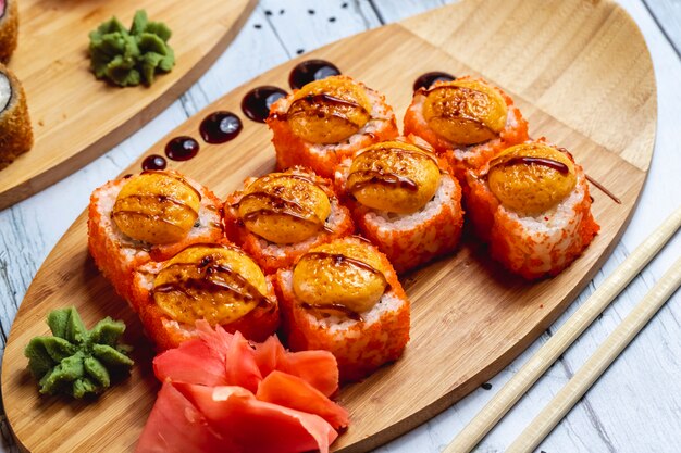 Rotolo di California al forno di vista laterale con wasabi e zenzero della salsa del caviale di tobiko del formaggio cremoso della carne di granchio su un bordo