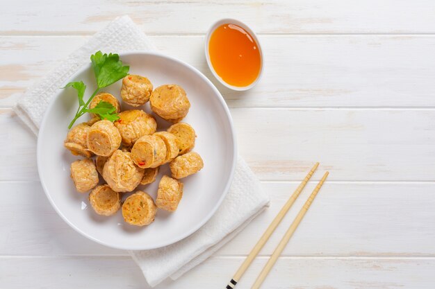 Rotolo di fhicken fritto in profondità sulla superficie di legno bianca.