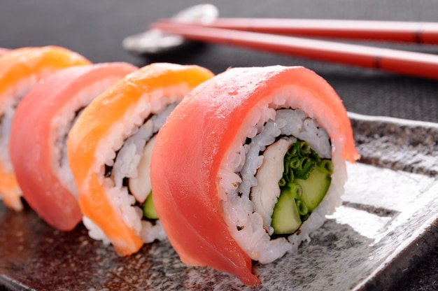 Rotolo di sushi di salmone con bacchette closeup