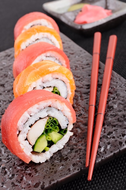 Rotolo di sushi di salmone con bacchette closeup