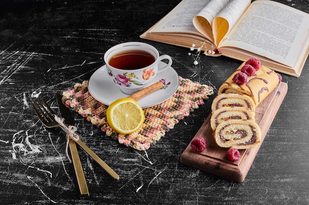 Rotolo di torta con cioccolato e frutti di bosco e una tazza di tè.