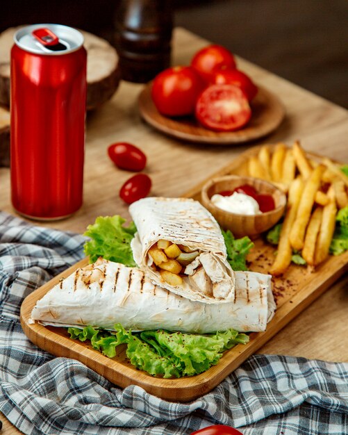 Rotolo e patate fritte della pita di pollo su un bordo di legno