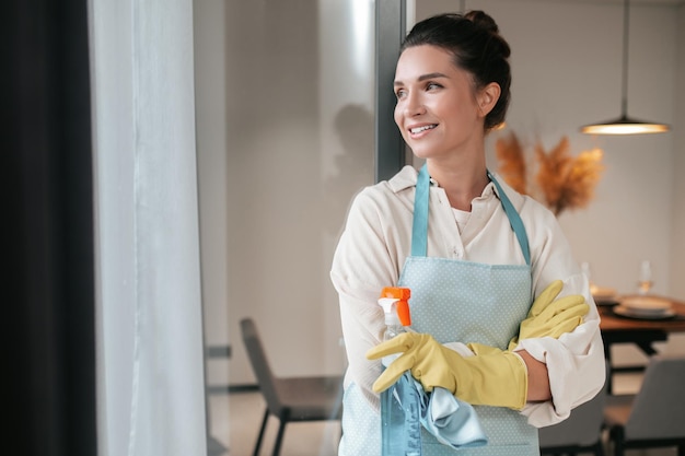 Routine domestica. Sorridente casalinga in grembiule in piedi in cucina