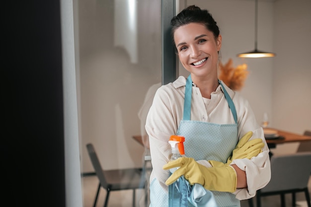 Routine domestica. Sorridente casalinga in grembiule in piedi in cucina