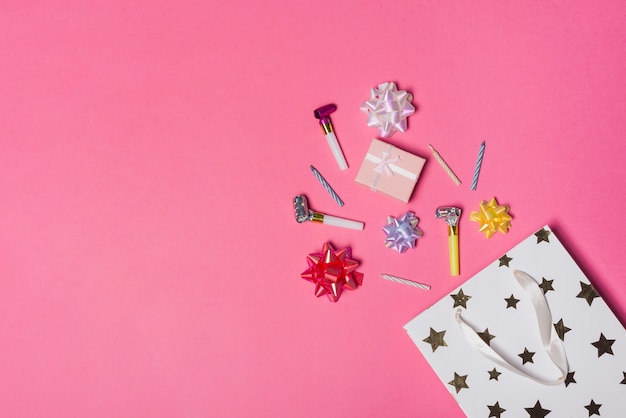Rovesciare l&#39;arco colorato di raso; pacco regalo; ventilatori e candele partito dal sacchetto di carta su sfondo rosa
