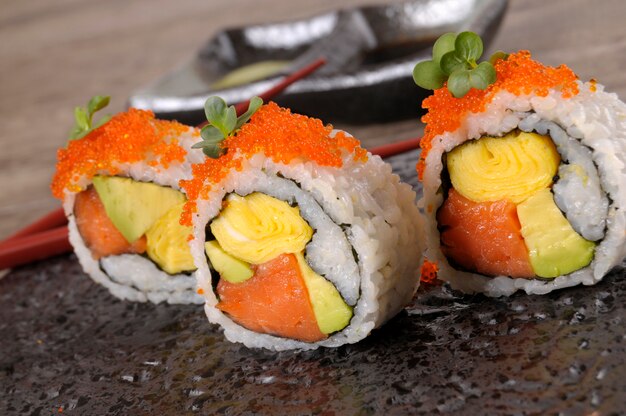 Rullo di sushi con il caviale su un piatto nero