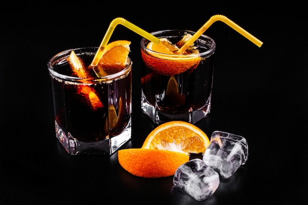 Rum e cola rinfrescanti cocktail alcolici in bicchiere highball con arancia e ghiaccio