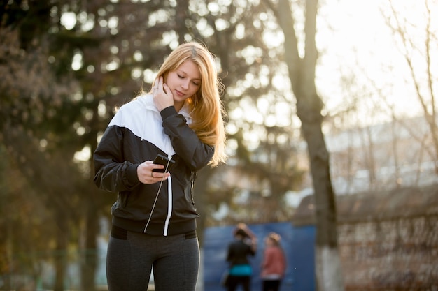 Runner ragazza con smartphone prima di jogging mattina