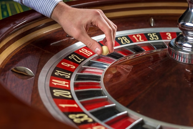 Ruota della roulette e mano del croupier con palla bianca nel casinò dettagli ravvicinati