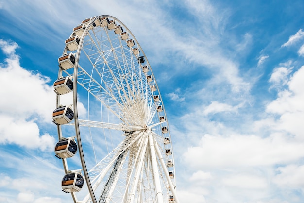 Ruota panoramica contro il cielo blu con nuvole