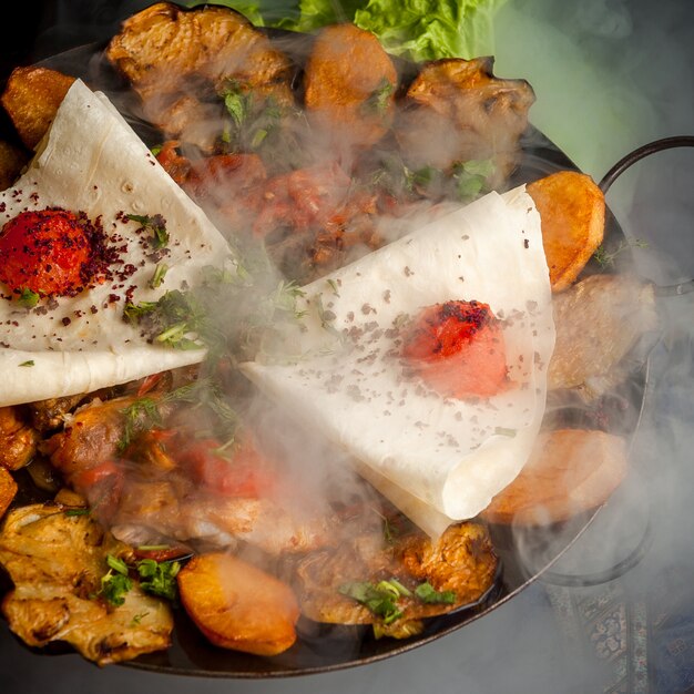 Sacca di pollo vista laterale con patate fritte e pomodoro e lavash in fumo