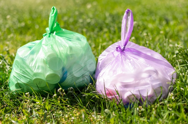 Sacchetti di plastica con rifiuti su erba