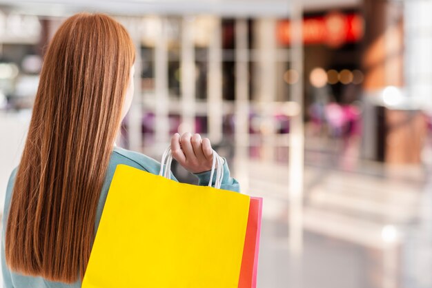 Sacchi di carta della tenuta della donna di vista posteriore