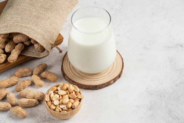 Sacco di arachidi tostate organiche e latte di vetro sul tavolo di marmo.