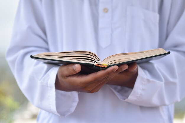 Sacro Corano in mano con significato di calligrafia araba di Al Quran.