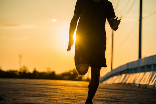 sagoma di un uomo giovane fitness in esecuzione su sunrise