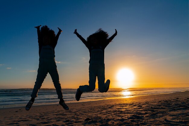 Sagome a figura intera di persone che saltano al tramonto