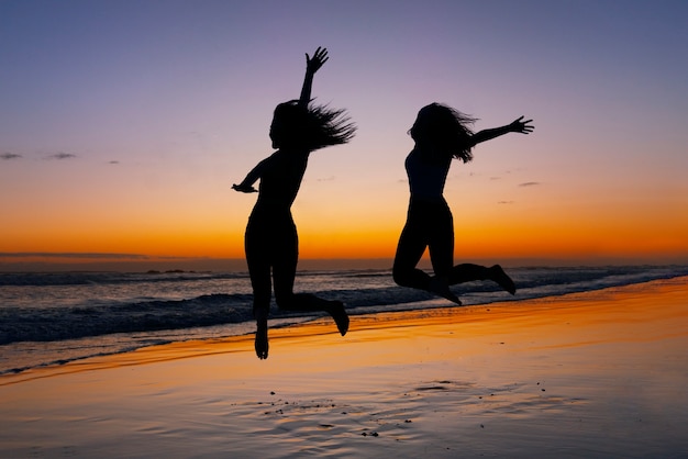 Sagome a figura intera di persone che saltano al tramonto