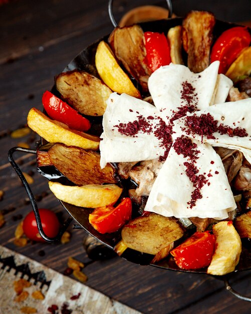 Saj di carne con patate melanzane e pane pita cosparsi di sumach