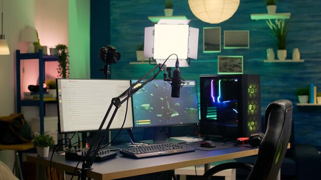 Sala di streaming vuota con computer potente professionale, tastiera e mouse RGB, cuffie e microfono