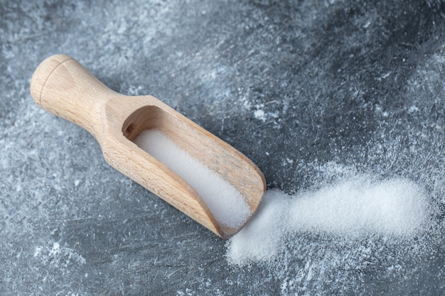 Sale in un cucchiaio di legno su uno sfondo di marmo.