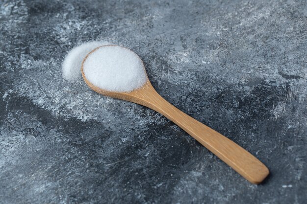 Sale in un cucchiaio di legno su uno sfondo di marmo.