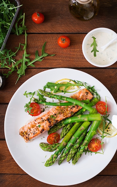 Salmone al forno guarnito con asparagi e pomodori alle erbe.