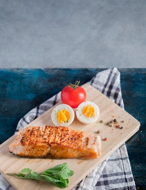 Salmone arrosto con uovo sodo su tavola di legno