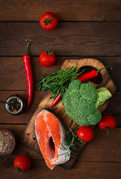 Salmone e verdure crudi della bistecca per la cottura sulla tavola di legno in uno stile rustico. Vista dall'alto