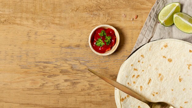 Salsa al pomodoro vicino al cucchiaio e alla tortiglia con calce affettata