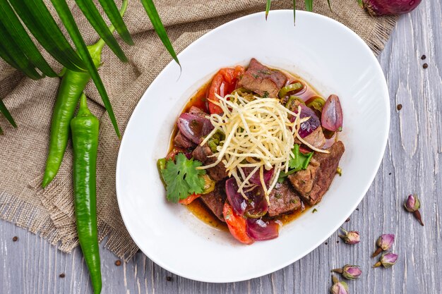 Salsa di carne vista dall'alto con verdure fritte e cipolle fritte con top e peperoncino