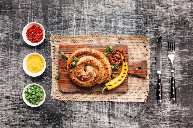 Salsicce alla griglia a spirale fatte in casa sul tagliere vicino ingrediente sano disposti in fila