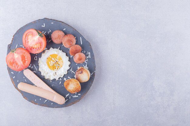 Salsicce bollite e fritte con l'uovo sul pezzo di legno.