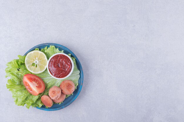 Salsicce fritte affettate e ketchup sul piatto blu. Illustrazione di alta qualità