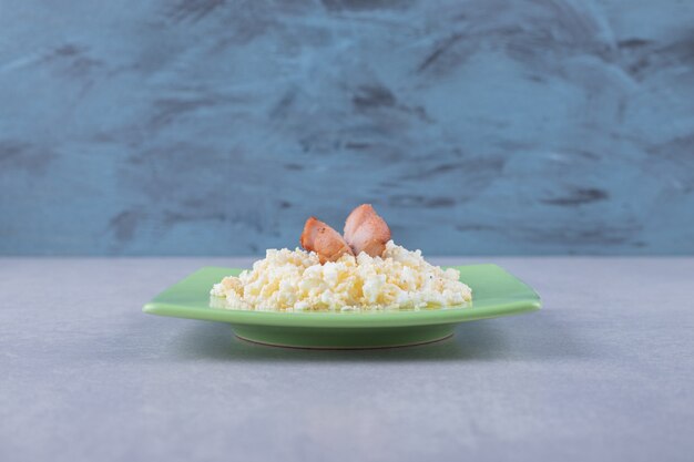 Salsicce fritte e maccheroni sul piatto verde.